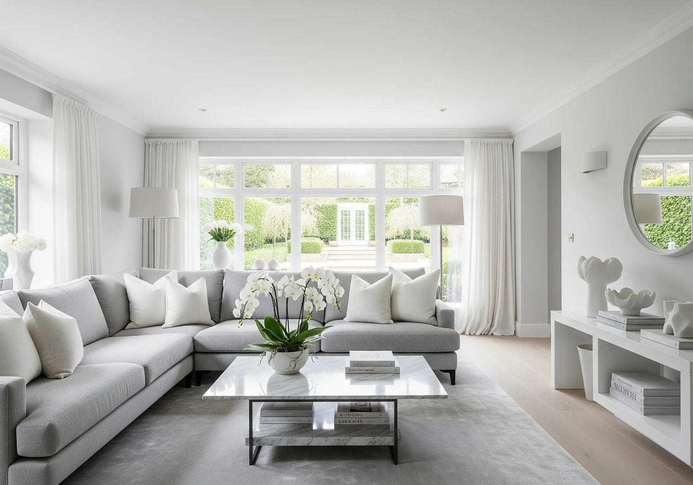 Modern living room with a gray sectional sofa, white walls, and large windows.